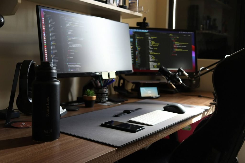 Modern desk setup with multiple monitors, light bar, and dark aesthetic
