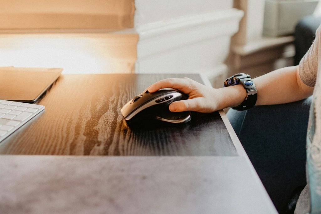 Person holding an ergonomic computer mouse at a home office desk